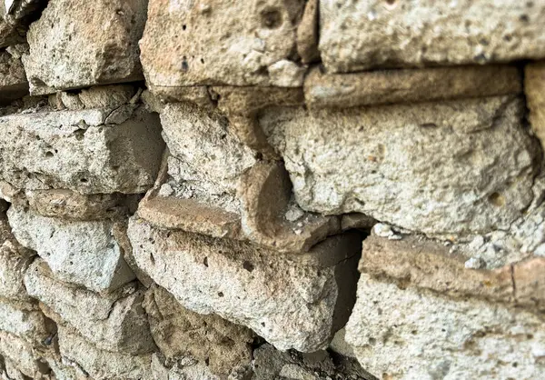 Doğal çatlaklara ve dokulara sahip eski ve pürüzlü bir duvara yakın çekim. Tasarım ve inşaat kavramları için kırsal bir arka plan. Yüksek kalite fotoğraf