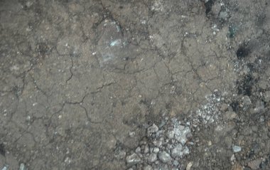 Çatlak ve yıpranmış asfalt dokusu ya da görünen küçük taşlar ve beyaz kalıntı parçalarıyla beton yüzey. Görüntü, eski ve hasarlı bir zeminin arka plan için ideal olduğunu gösteriyor.