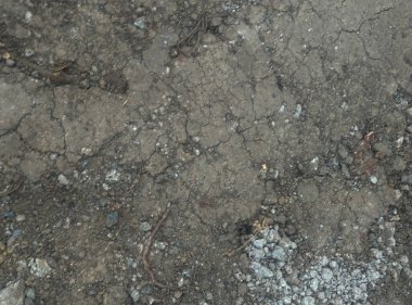 Çatlak ve yıpranmış asfalt dokusu ya da görünen küçük taşlar ve beyaz kalıntı parçalarıyla beton yüzey. Görüntü, eski ve hasarlı bir zeminin arka plan için ideal olduğunu gösteriyor.