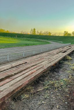 Boş futbol sahası günbatımının fotoğrafı. Eski stadyum. Yüksek kaliteli ahşap banklar.