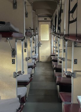 Dar koridorlu ve ranzaları açık olan eski Sovyet tarzı bir vagon. Fotoğraf, Doğu Avrupa demiryolu seyahatlerinde kullanılan bir kompartman platformunun tipik yerleşimini gösteriyor