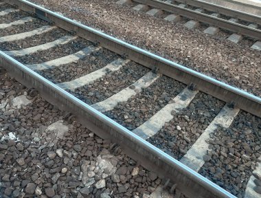 Gün batımında sessiz bir tren istasyonunda kıvrımlı tren rayları. Sahnede birden fazla demiryolu hattı, elektrik kabloları ve birkaç uzak yayası olan terk edilmiş bir platform yer alıyor. Sıcaklık