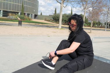 Sporcu kadın bir parkta çalışmaya başlamadan önce ayakkabı bağcıklarını bağlıyor.