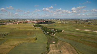 Yukarıdan ekilmiş tarlalar, gölet ve kırsal köy, huzurlu bir kırsal alan yaratıyor.