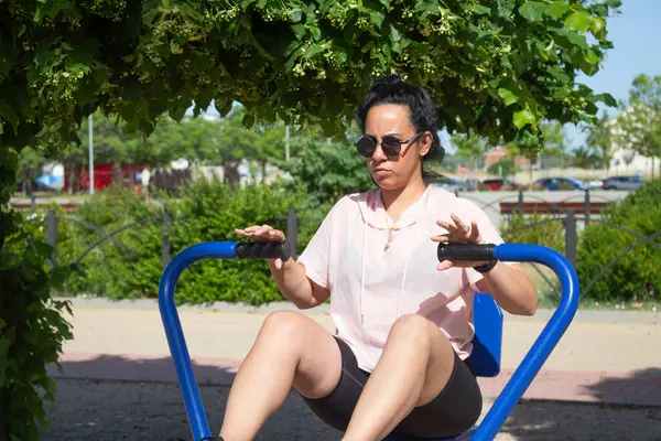 Dışarıda spor salonunda kürek çeken bir kadın.