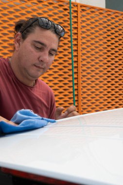 Araba yıkama işçisi, mavi mikrofiber bezle araç çatısını cilalıyor, kusursuz bir bitiş ve müşteri memnuniyeti sağlıyor.