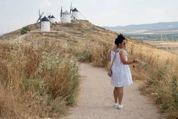 İspanya 'da tarihi yel değirmenlerinin yakınında yürüyen bir kadın.