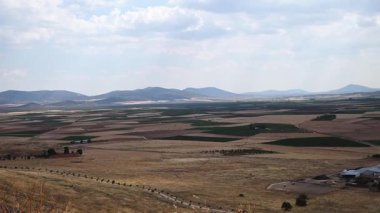 Türkiye 'nin Merkez Anadolu kentinde geniş tarlalar ve tarlalar bulutlu bir gökyüzü altında uzanıyor