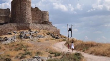 Bir tepedeki şatoya doğru yürüyen turistler.