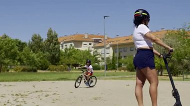 Şehir parkında elektrikli scooter kullanan genç bir kadın.