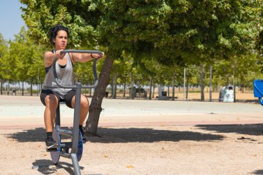 Spor salonunda egzersiz bisikleti kullanan konsantre bir kadın.