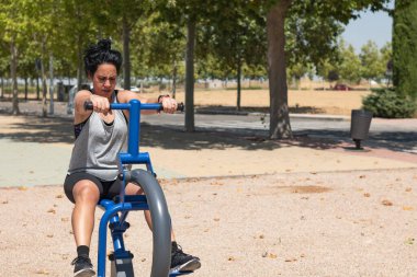 Açık hava spor salonunda kürek çeken kararlı bir kadın sağlıklı bir yaşam tarzı ve kondisyonu destekliyor.