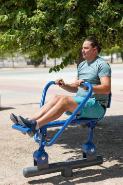 Adam parkta mavi bir eğitim makinesiyle çalışıyor.