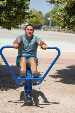 Açık hava spor salonunda kürek çeken kararlı bir adam.