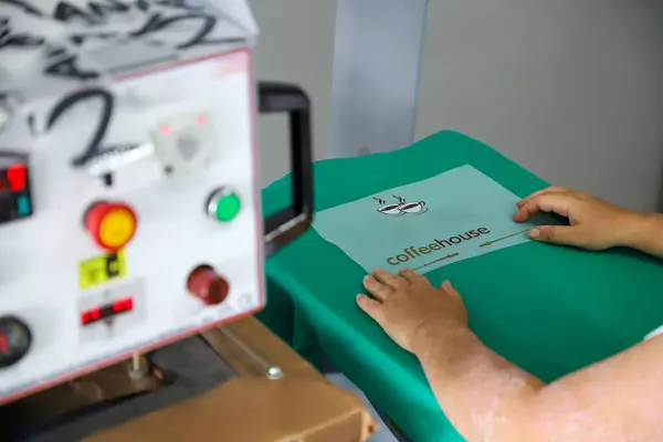 Renkli tişörtlere baskı yap, kumaşlara resim basmak için bas. Erkek işçiler için tekstil yazdırırken büyük endüstriyel tekstil baskı makinesi.