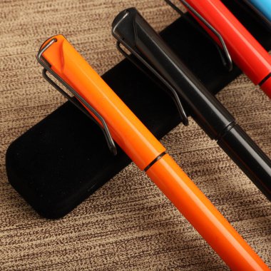 Colorful Assorted Pens Arranged Neatly on a Textured Surface clipart
