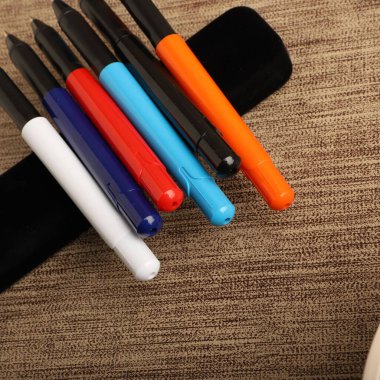 Colorful Assorted Pens Arranged Neatly on a Textured Surface clipart