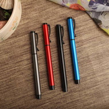 Colorful Assorted Pens Arranged Neatly on a Textured Surface clipart