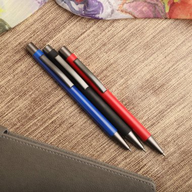 Colorful Assorted Pens Arranged Neatly on a Textured Surface clipart