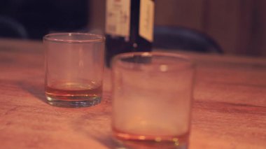 Samimi Bar Sahnesi. Yüksek kalite 4K görüntü. Kırsal bir ahşap masaya yerleştirilmiş, katmanlı bir kokteyl veya içecekle iki kısa bardağı içeren yumuşak odaklı bir görüntü..