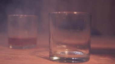 Samimi Bar Sahnesi. Yüksek kalite 4K görüntü. Kırsal bir ahşap masaya yerleştirilmiş, katmanlı bir kokteyl veya içecekle iki kısa bardağı içeren yumuşak odaklı bir görüntü..