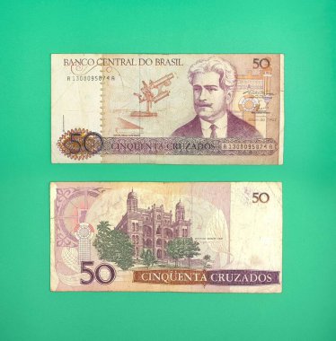 Brezilya 'dan iki adet 50 Cruzados notu, içinde bilim adamı Santos Dumont' un bir portresi ve şatonun canlı yeşil bir arkaplan üzerinde resmedilmiş, nostalji ve ekonomik tarihi çağrıştıran.