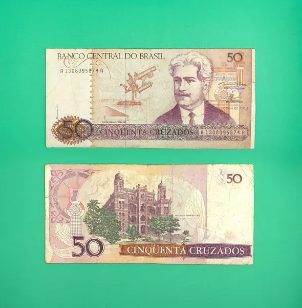 Brezilya 'dan iki adet 50 Cruzados notu, içinde bilim adamı Santos Dumont' un bir portresi ve şatonun canlı yeşil bir arkaplan üzerinde resmedilmiş, nostalji ve ekonomik tarihi çağrıştıran.