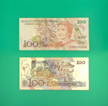 Canlı yeşil bir arkaplan üzerine iki Brezilya 100 cruzeiro notu. Üst notada tarihi bir figürün portresi yer alırken, alt notada çocuk kitapları ve doğa öğeleri yer alıyor. Brezilya ekonomisinin nostaljik bir temsili.