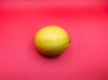 Parlak kırmızı arka planda sarı bir limonun canlı bir görüntüsü. Renk kontrastı limon dokusunu vurgular, tazelik ve canlılık uyandırır.