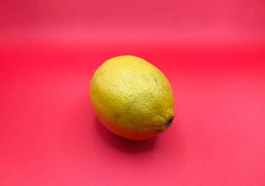 Parlak kırmızı arka planda sarı bir limonun canlı bir görüntüsü. Renk kontrastı limon dokusunu vurgular, tazelik ve canlılık uyandırır.