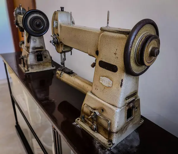 Ahşap bir standın üzerinde eski moda tasarımlarını ve eski metal detaylarını vurgulayan iki eski tip dikiş makinesi nostaljiyi ve moda evrimini ve yıllar boyunca dikiş dikmeyi çağrıştırıyor..