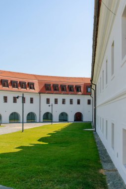 Nefes kesici bir manzara, berrak mavi gökyüzünün altında yemyeşil çimlerle birlikte tarihi mimariyi sergiliyor.