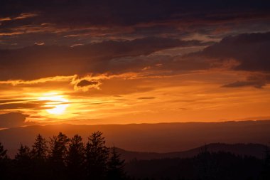 Nefes kesici ve nefes kesici bir gün batımı dingin ve sakin bir dağ manzarasında canlı turuncu renkler sergiliyor.