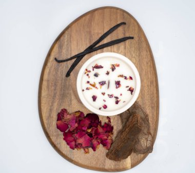 Çiçek ve aromatik malzemelerin ahşap bir tabakta ustalıkla sunulduğu uyumlu bir düzen.