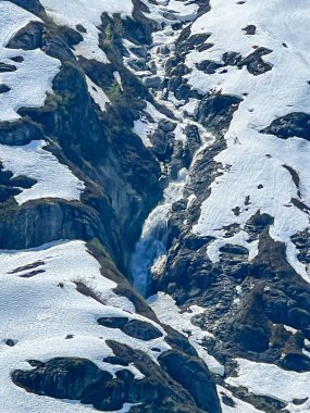 Sersemletici bir şelale engebeli bir dağ geçidinden geçer, kar ve buzu keser. Doğanın gücü ve güzelliği Alp Harikalar Diyarı 'nda sergileniyor..  