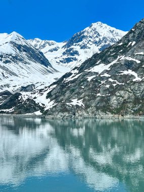 Alaska, Buzul Körfezi 'nin sakin sularında karla kaplı dağların çarpıcı bir görüntüsü yansıyor. Engebeli arazi ve huzurlu yansımaların mükemmel bir karışımı..