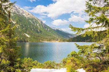 Baharda Alp Gölü 'nün manzarası. Karda, Rysy Kayaları 'nın yanında güzel bir manzara. gökyüzü ve bulutlarla seyahat arkaplanı