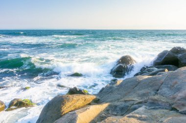 Yazın Karadeniz 'de kayalar. Güneşli bir sabahta kıyıya vuran dalgalar. Bulutsuz mavi gökyüzü. Deniz kenarında seyahat geçmişi. Gökyüzünde bulut yok