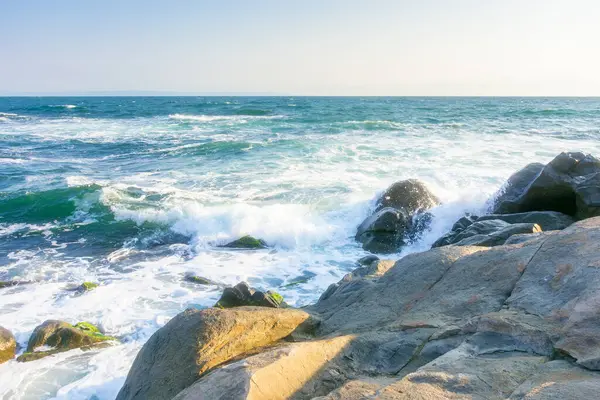 Yazın Karadeniz 'de kayalar. Güneşli bir sabahta kıyıya vuran dalgalar. Bulutsuz mavi gökyüzü. Deniz kenarında seyahat geçmişi. Gökyüzünde bulut yok
