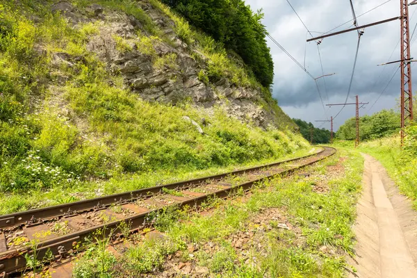 Dağ demiryolu seyahat geçmişi. Bulutlu mavi gökyüzü. Yazın Avrupa 'nın güzel ulaşım manzarası. Güneşli bir günde eski tren yolu geçidi