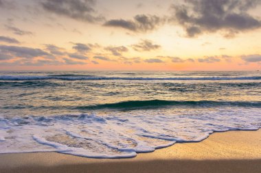 Deniz dalgası şafakta kumsala değecek. Sozopol 'da yaz tatili. Doğa, parlak turuncu gökyüzü ve kara bulutlar altında huzur dolu rüyalar. Sakin suyu olan deniz manzarası ve rahatlama havası.