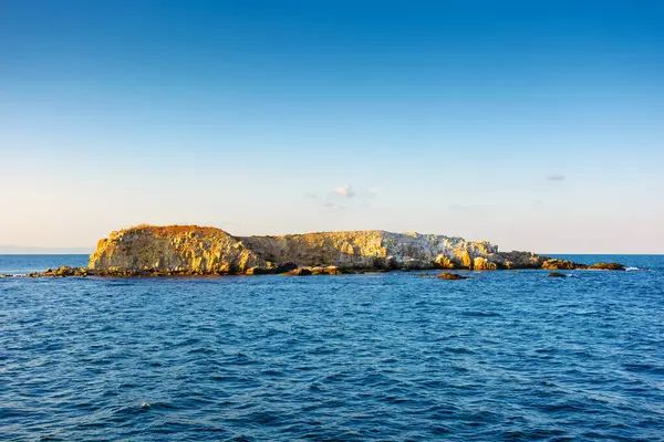 Akşamüstü Karadeniz 'de kaya adası manzarası. Yaz maceraları için sakin dalgalarla dolu engebeli bir arazi. Mavi gökyüzünün altında bulutlarla birlikte.