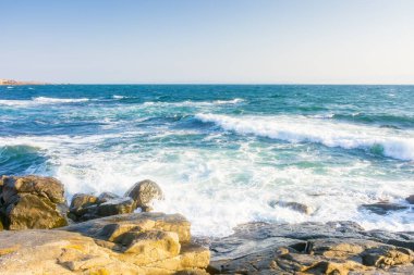 Yazın Karadeniz 'de kayalar. Güneşli bir sabahta kıyıya vuran dalgalar. Bulutsuz mavi gökyüzü. Deniz kenarında seyahat geçmişi. Gökyüzünde bulut yok