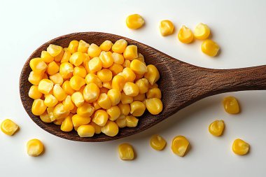 Büyüleyici yakın çekim gösterileri canlı sarı mısır çekirdekleri ile dolup taşan kırsal ahşap bir kaşık, temiz beyaz bir yüzeye karşı tezat oluşturarak görsel olarak çekici bir yiyecek natürmort hayat yaratıyor..