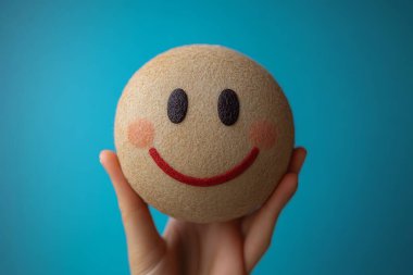 Kalıplı, siyah gözlü, kırmızı gülüşlü ve elinde pembe allık olan bej bir topa yakından bak. Mutlu duyguları vurgulayan parlak bir arkaplan..