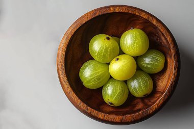 İnce dokuları olan yeşil benekli böğürtlenlerin üst görüntüsü, el yapımı, kırsal ahşap bir kasenin içinde düzgünce düzenlenmiş, kompozisyona sıcaklık katıyor..