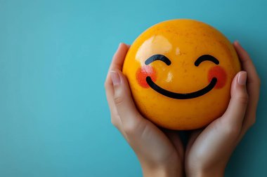 Duygusal sanat eserleri neşeli, yuvarlak, sarı bir ifade sunar. Gül gibi yanakları ve geniş bir gülümsemesi vardır. Yumuşak, açık mavi bir zemin üzerine kurulmuş insan ellerinde nazikçe tutulur..