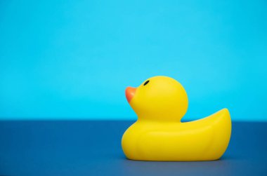 Mavi ve açık mavi arka planda sarı plastik bir ördek..