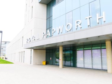 Cambridge, Cambridgeshire / Birleşik Krallık - 25 Nisan 2025: Royal Papworth Hastanesi, Cambridge, Birleşik Krallık. Gün ortası gri gökyüzü ve insanlar girişte yürüyorlar.