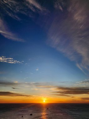Güneş Promthep Burnu 'ndan (Phuket, Tayland) batıyor. Durgun denizin üzerindeki gökyüzünü botlarla turuncuya boyuyor. 